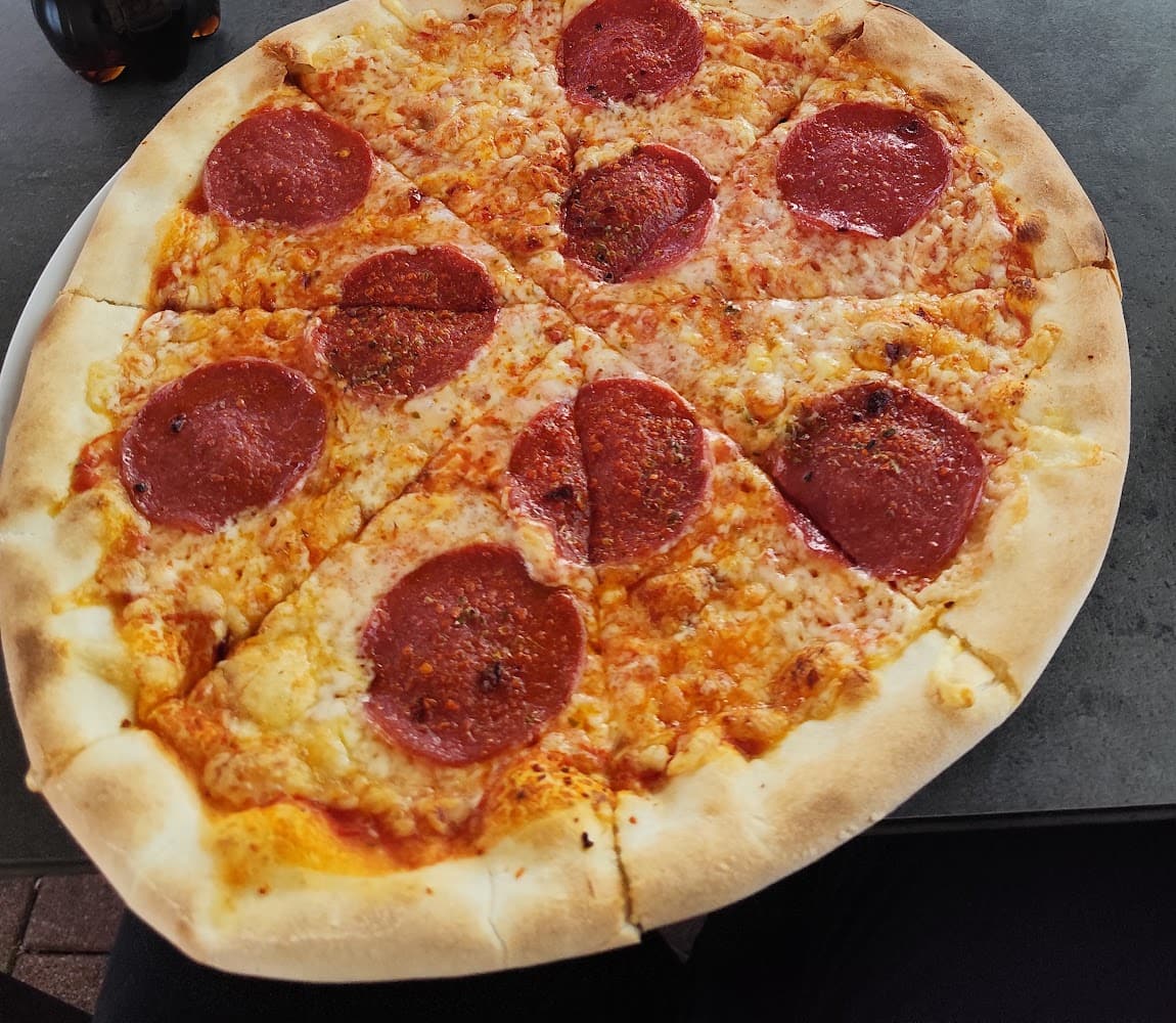 Pizza mit Salami von Happy Snack auf einem Tisch im Gastgarten